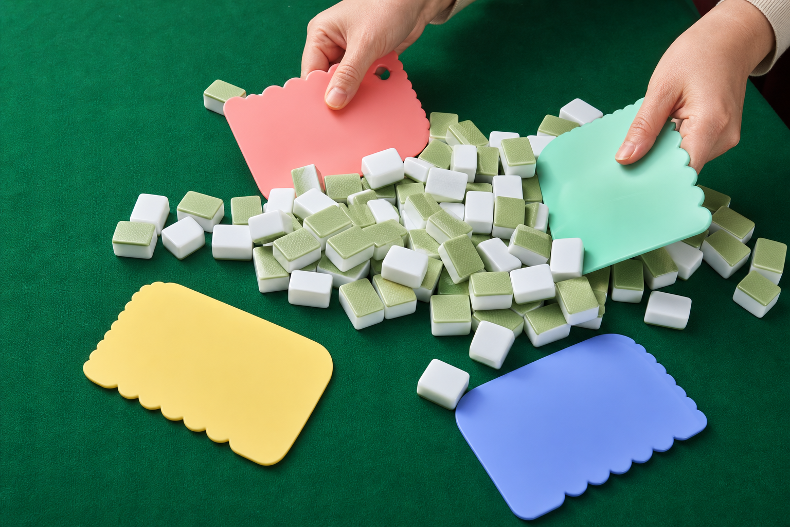Four colorful Mahjong shuffler cards being used to mix face-down tiles on a green table